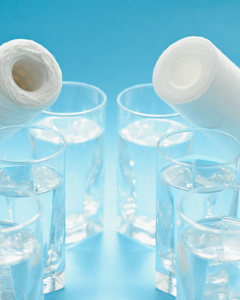 Glasses of dirty and clear water and filter cartridges to domestic water treatment systems